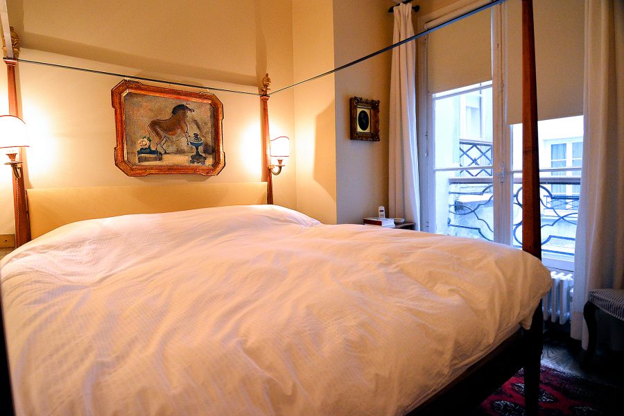 The master bedroom (4-poster, queen-sized bed) has windows overlooking the gallery-lined streets of Saint-Germain, Paris.