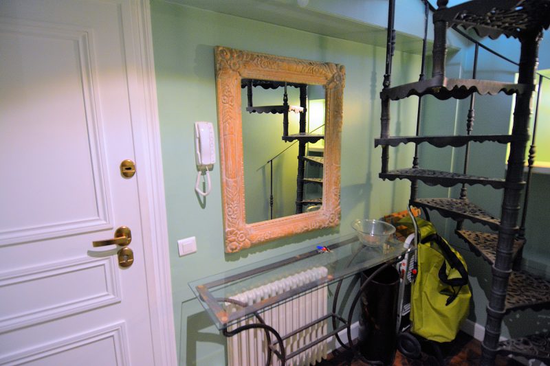 A wrought iron spiral staircase leads to the apartment's upper floor.