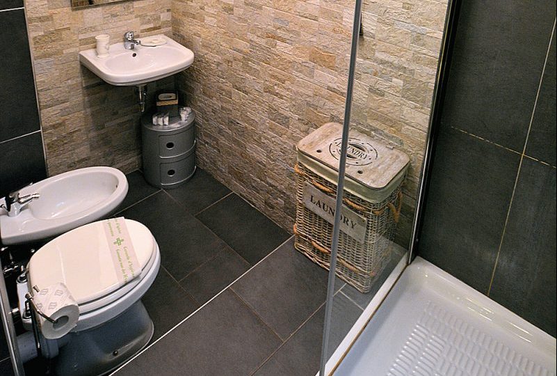 The Tiber Apartment: stone and tile mezzanine bathroom with shower.