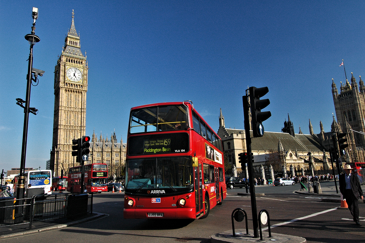 Double-decker bus 159 turning at Parliament Square between Big Ben and Westminster Abbey.