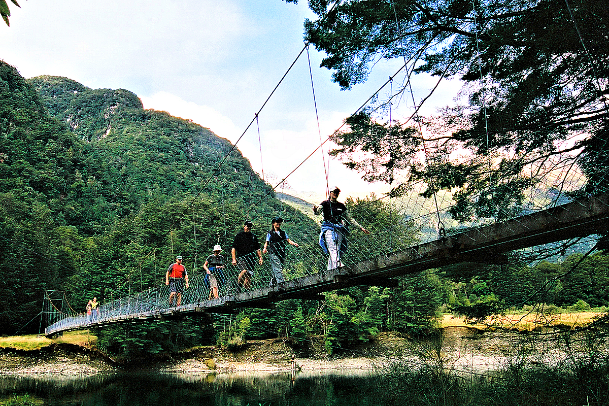 Fiordland: Milford Track hikers crossing swing bridge. Photo © Home At First.