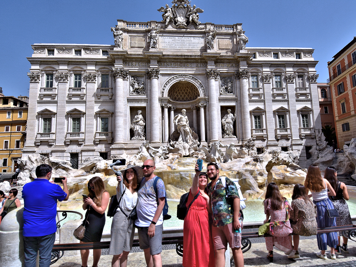 Tourists flock to the Trevi Fountain for selfies and to toss coins into the water. Photo © Home At First.