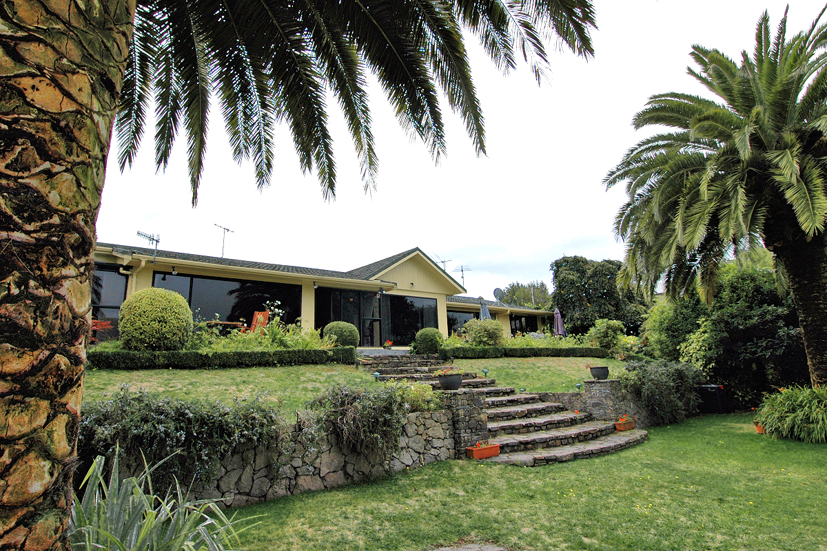 Rainbow Lodge exterior with palms. Photo © Home At First.